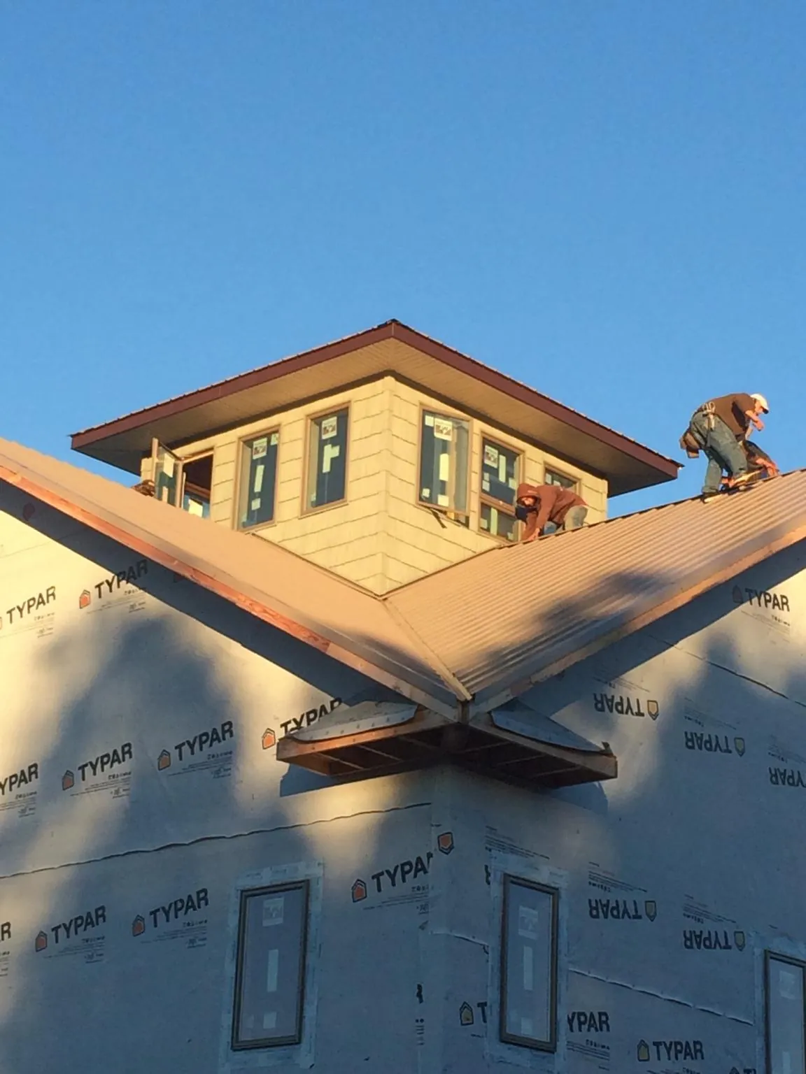 Roofers working around a rooftop cupola on a new metal roof at sunset — Roof Waterproofing in Little Rock by Roofing Brothers